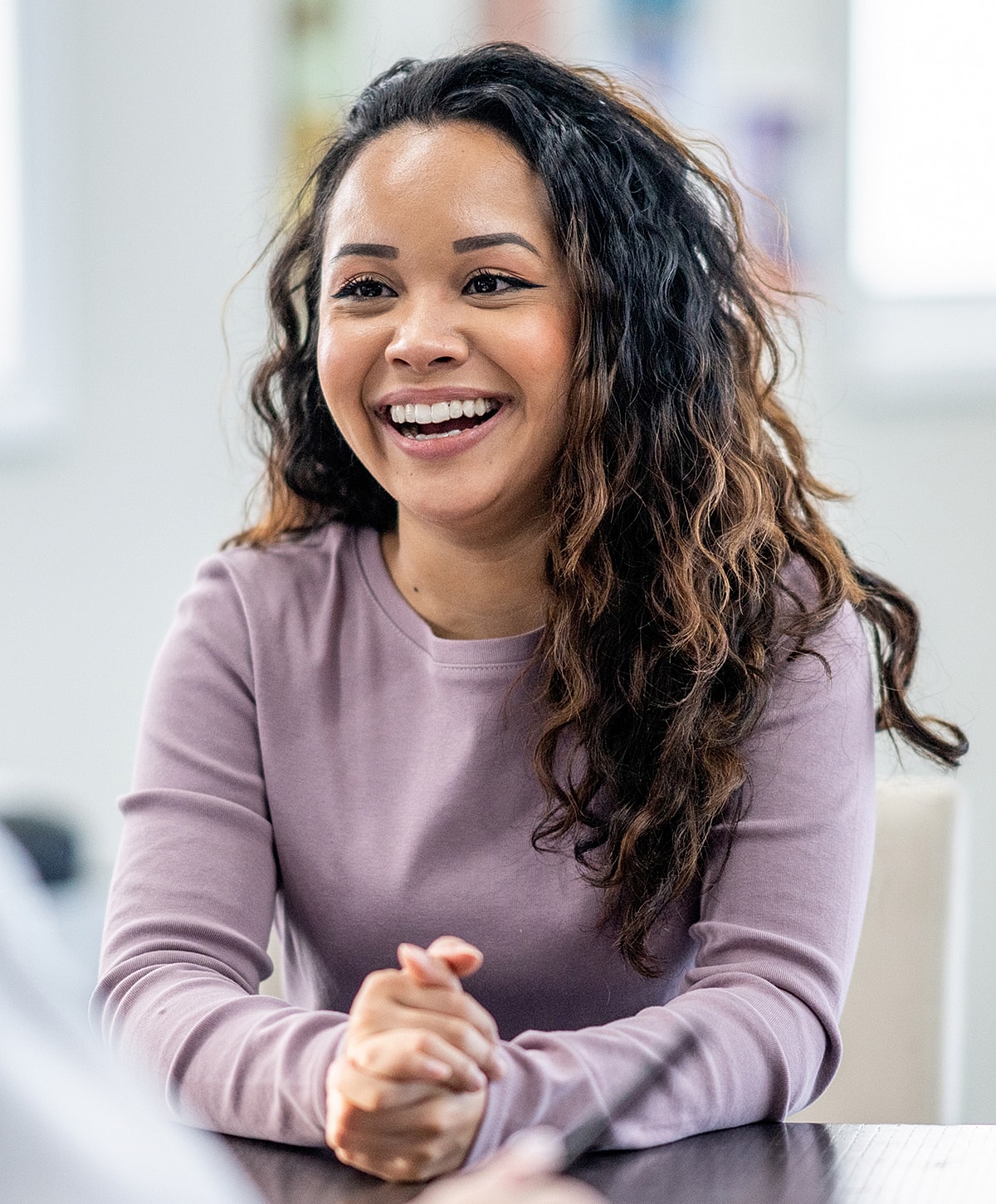 Smiling woman with curly hair in conversation.