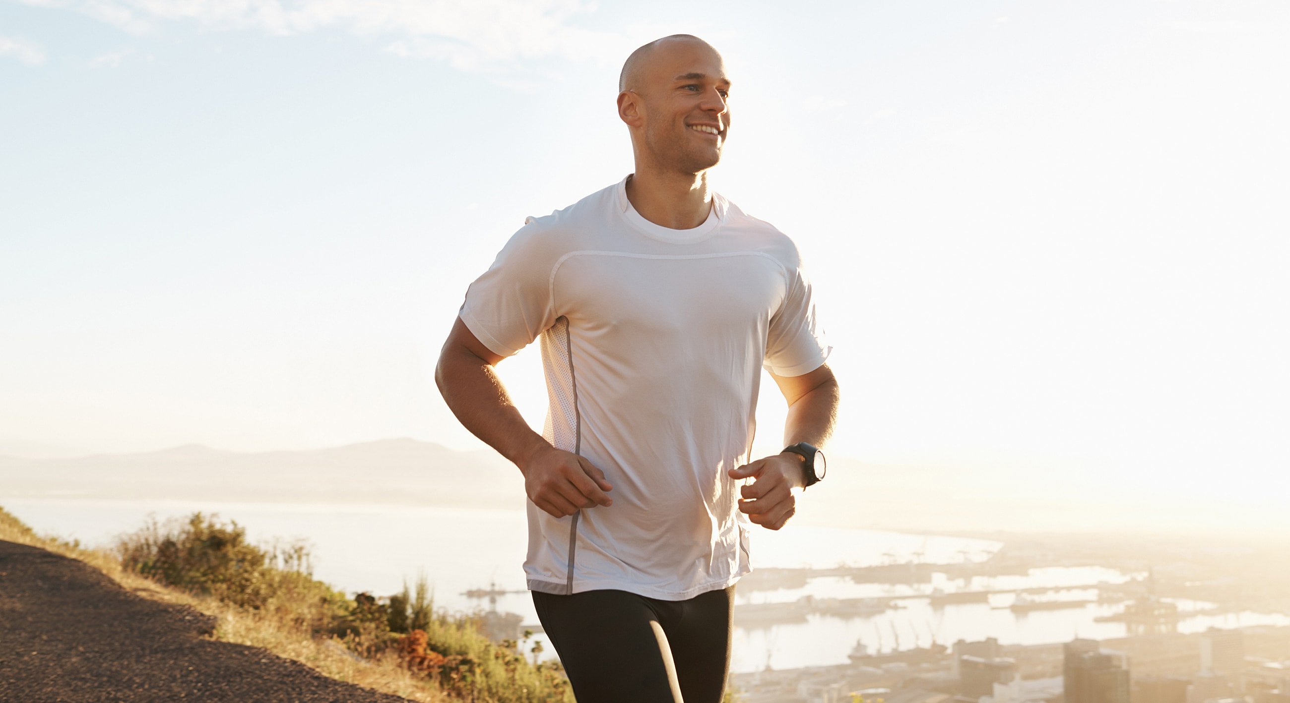 Man jogging outdoors with scenic background.